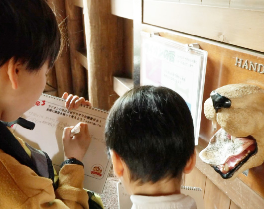 展示コーナーで動物の口の模型を観察しながらワークシートに記入する子どもたち。